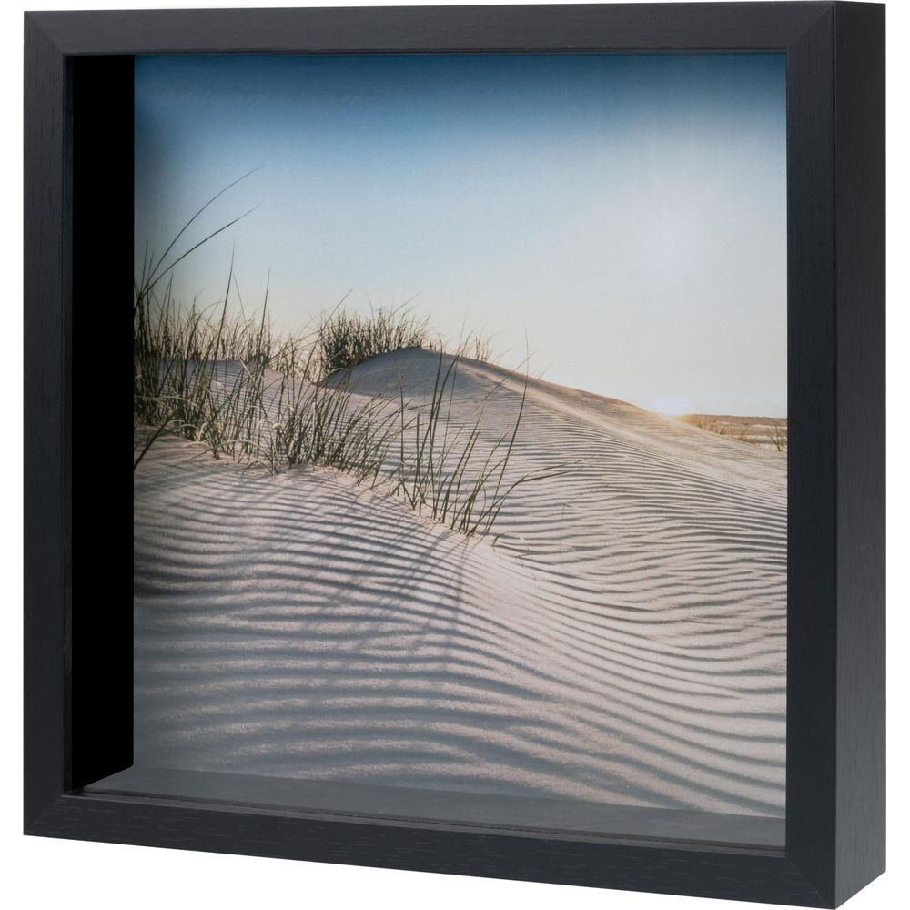 Dunes de sable avec de l'herbe et des motifs de vagues dans le sable sous un ciel bleu.