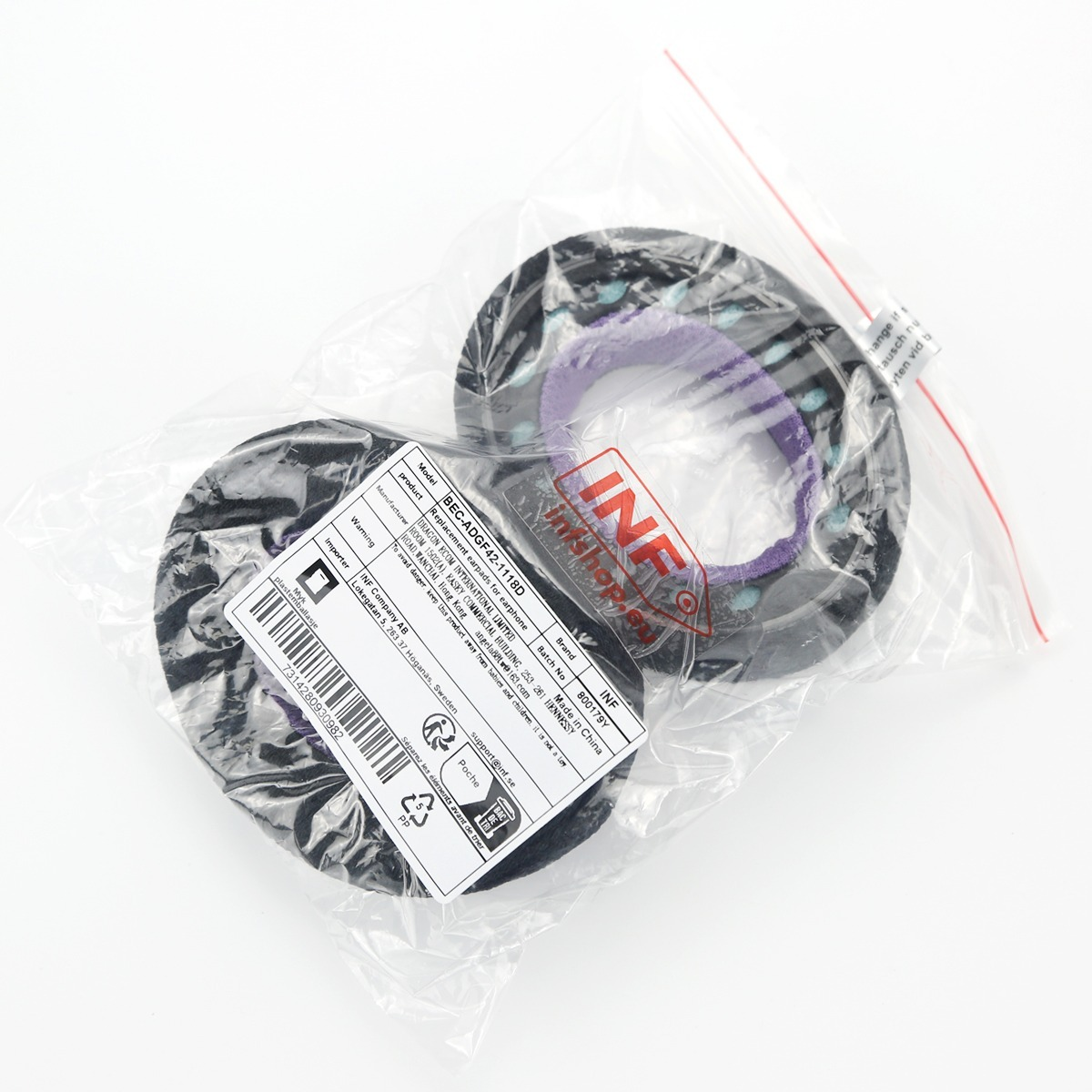 Due paraorecchie neri e viola in un sacchetto di plastica con etichetta.