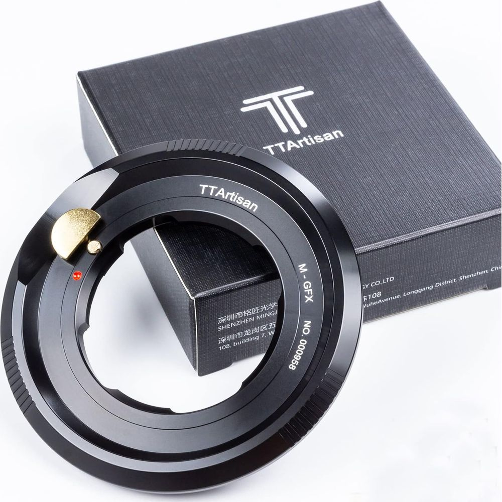 Un adaptateur d'objectif TTArtisan noir est devant une boîte noire avec le logo TTArtisan.