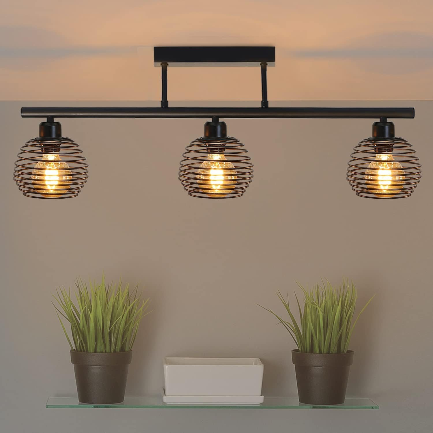 Lampada da soffitto con tre paralumi a globo in filo metallico e lampadine.