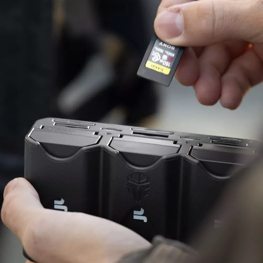 Una mano tiene una scheda SD Sony sopra un astuccio nero per schede di memoria.