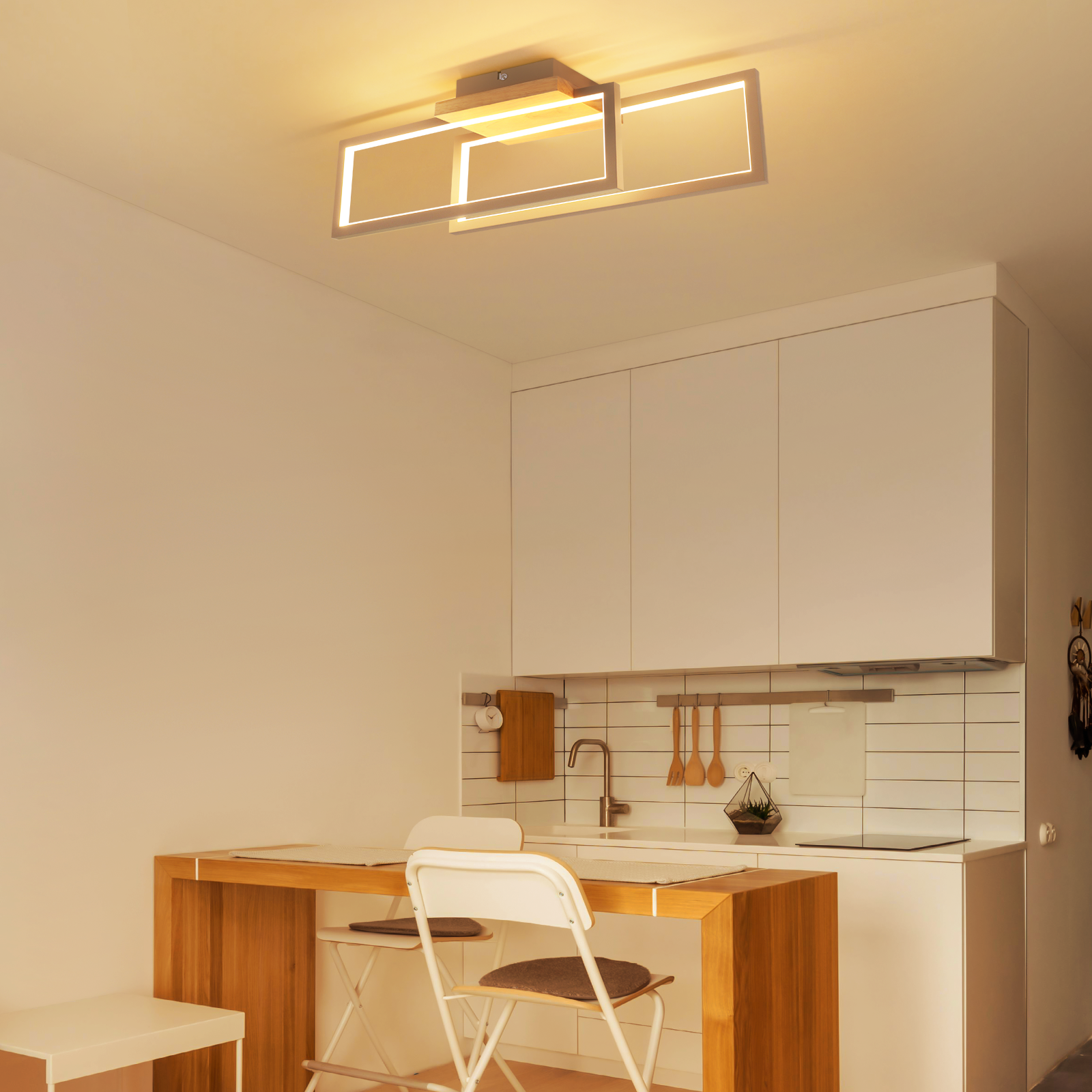 Una cucina moderna con tavolo in legno, sedie bianche e lampada da soffitto elegante.