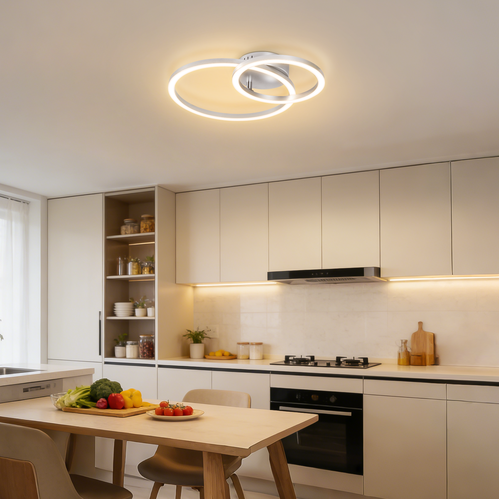 Cucina moderna con zona pranzo, illuminata da una plafoniera ad anello.