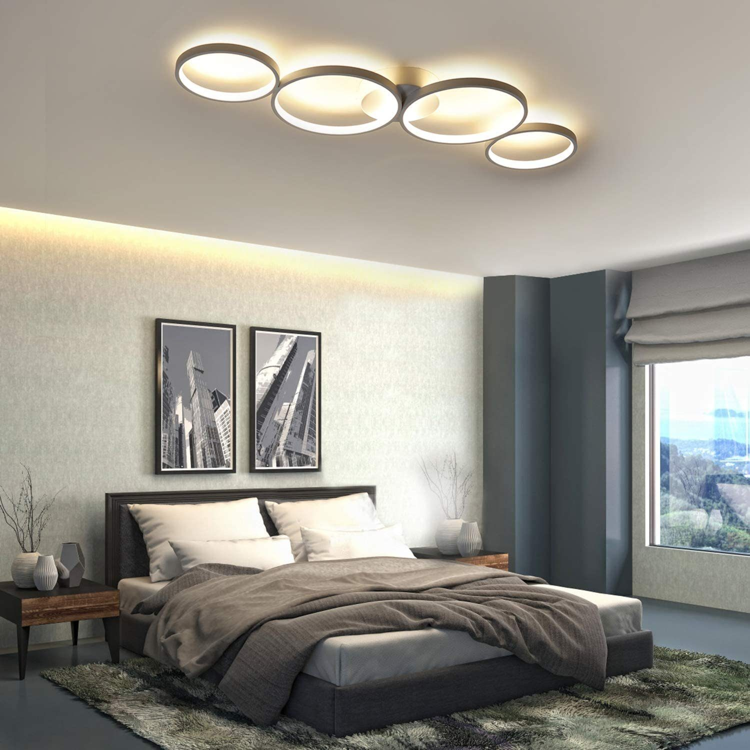 Una camera da letto moderna con un grande letto, due quadri di paesaggi urbani incorniciati e una lampada da soffitto ad anello.