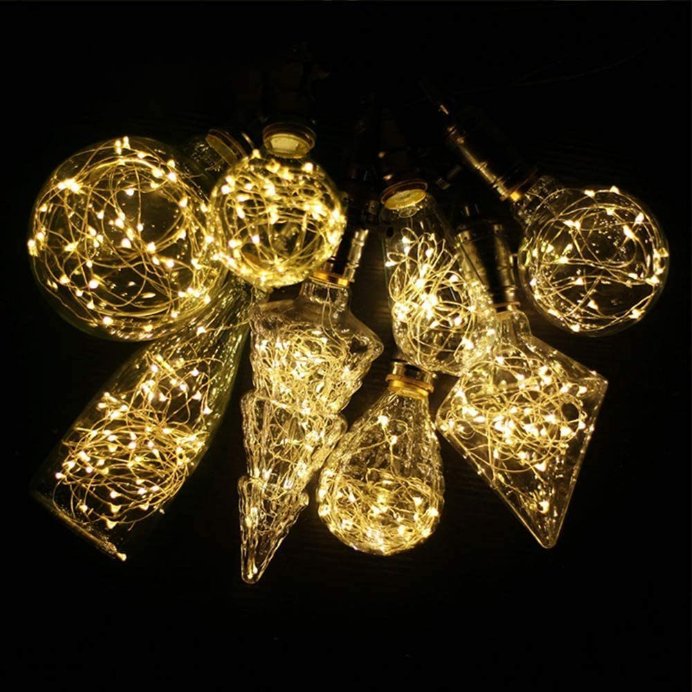 Mehrere Glaslampen mit warmweißen Lichterketten im Inneren auf schwarzem Hintergrund.