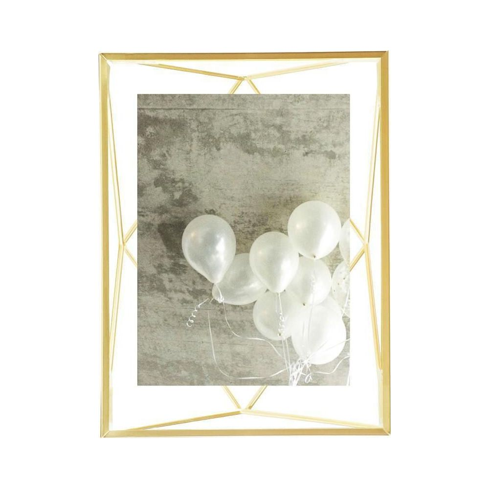 Cadre doré avec ballons blancs sur mur de béton.