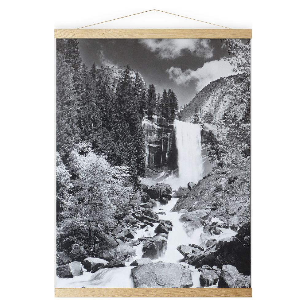 Ein Wasserfall stürzt über felsige Hänge, umgeben von Bäumen und Wolken.