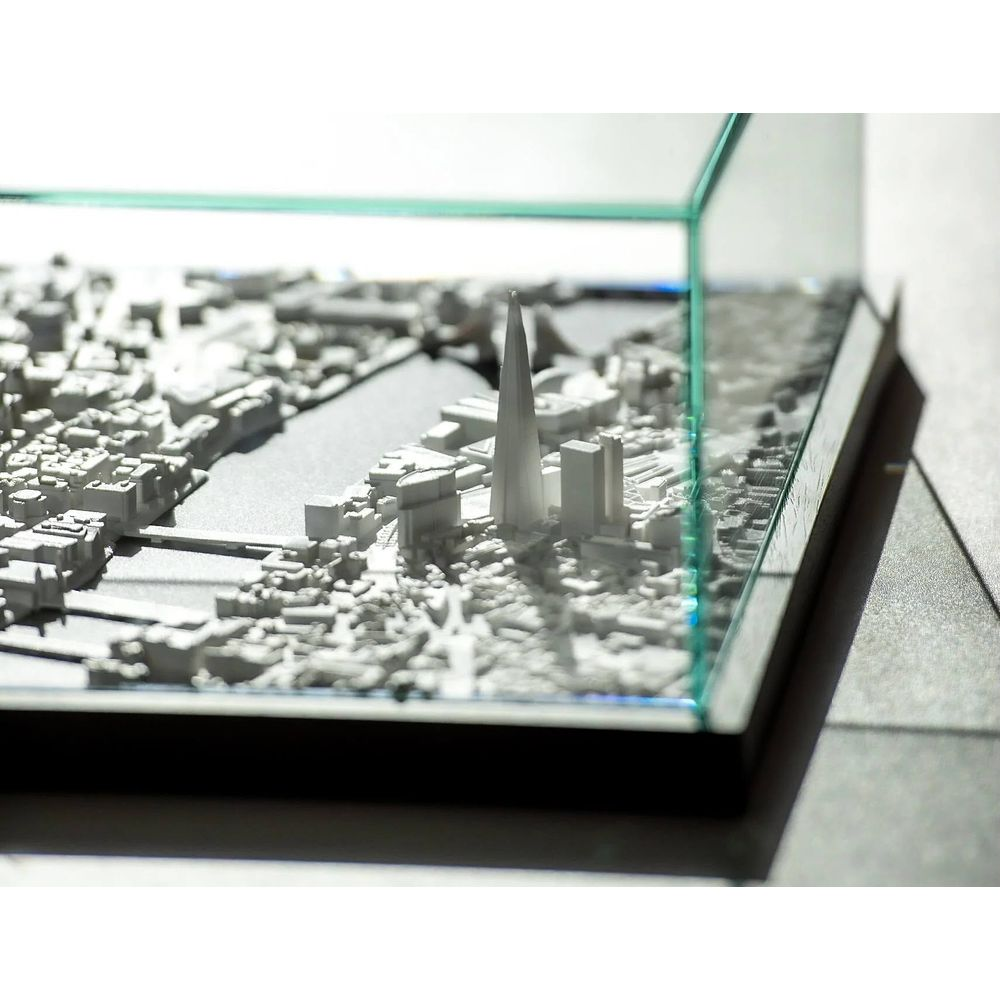 Un modèle de ville miniature blanc avec un boîtier en verre et une haute tour.