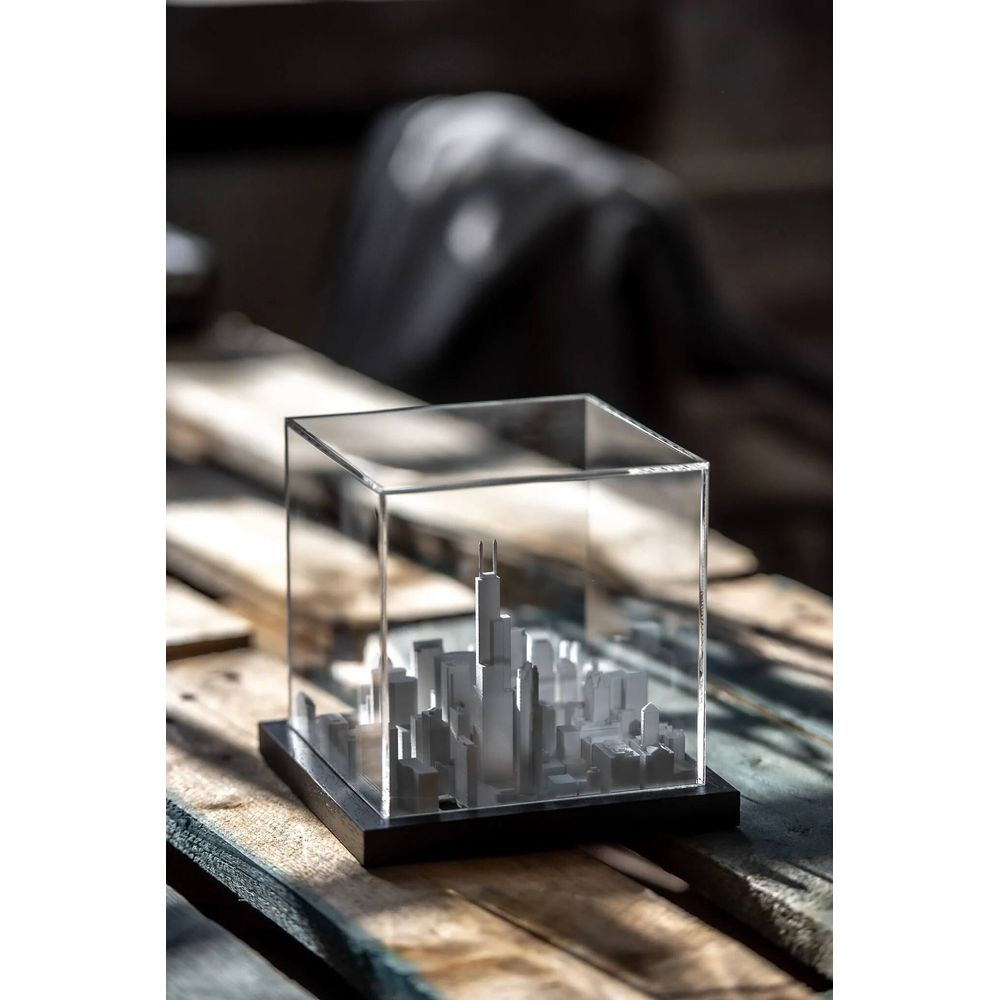Une maquette de ville avec des gratte-ciel dans une boîte en verre sur du bois.