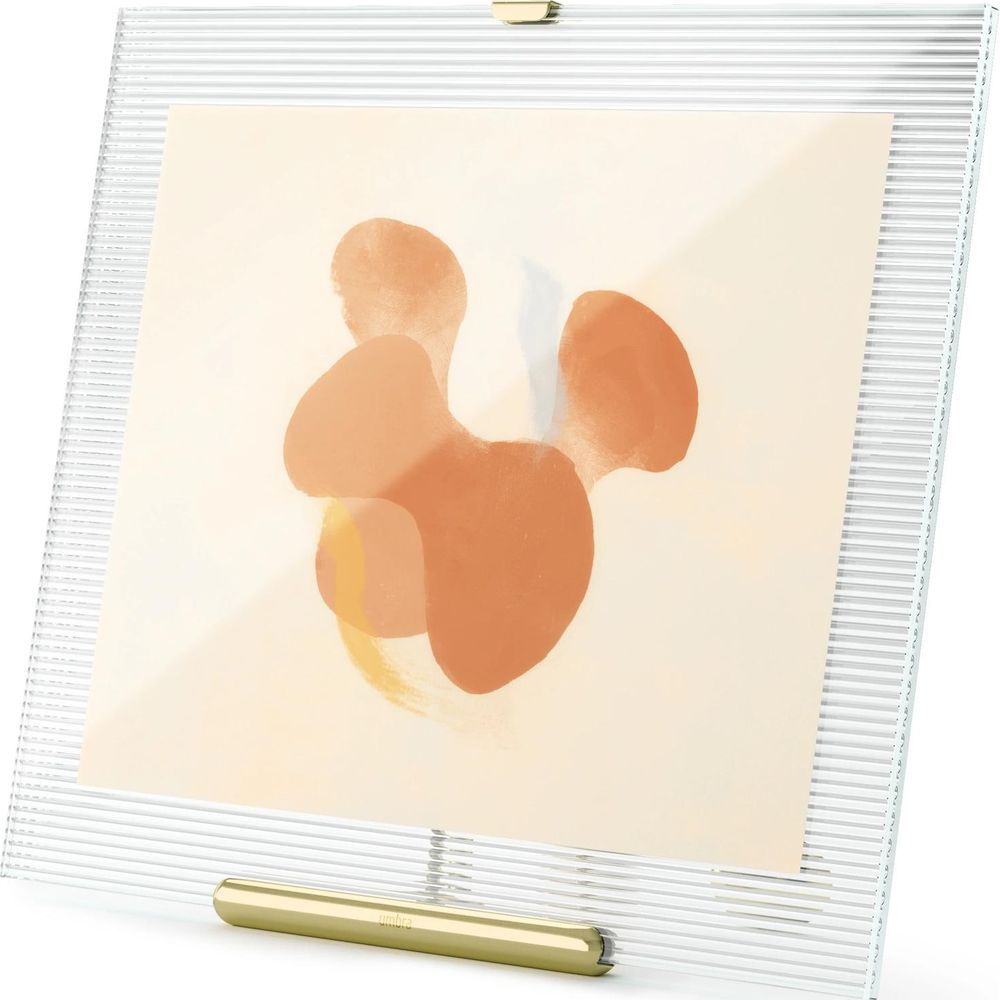 Un cadre en acrylique transparent présente une œuvre d'art abstraite dans des tons orange et beige.