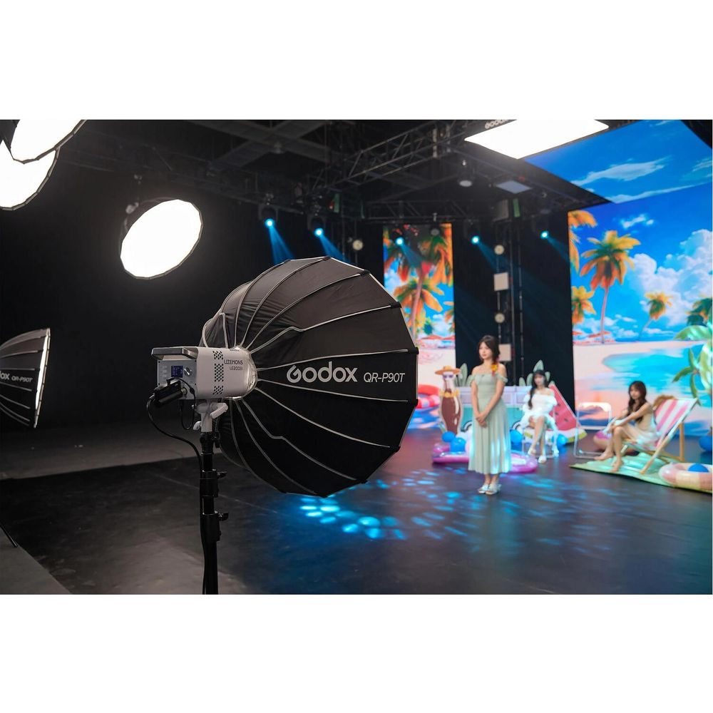 Ein Godox-Licht mit Softbox steht im Vordergrund. Drei Frauen sind im Hintergrund aufgestellt.