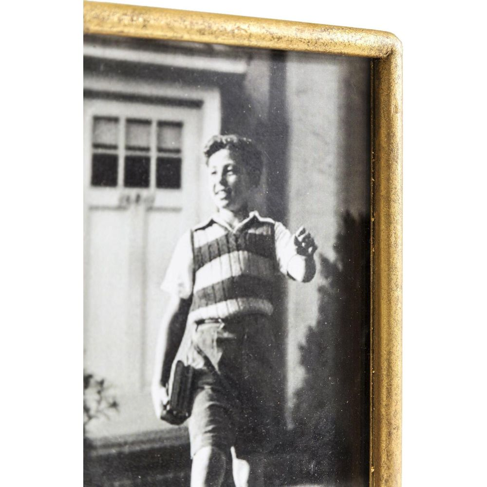 Ragazzo in gilet a righe e pantaloncini tiene libro, cammina verso porta.