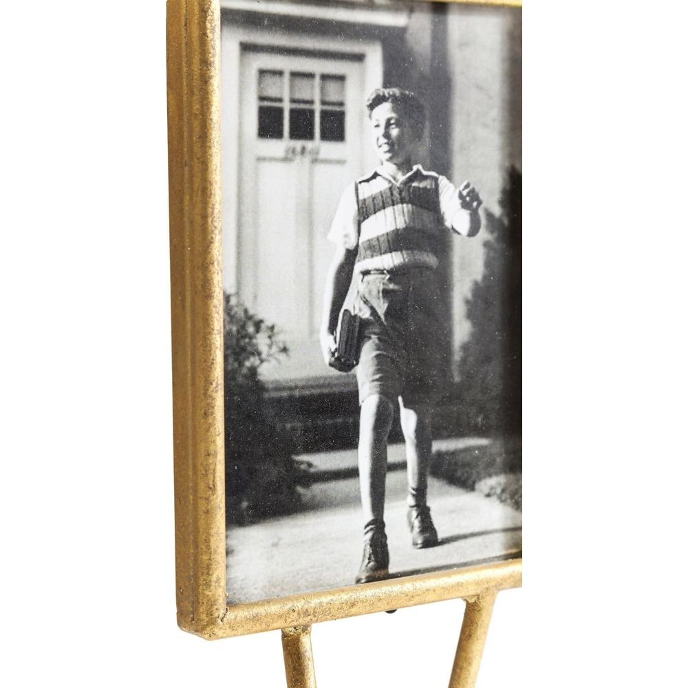 Un ragazzo in gilet e pantaloncini cammina tenendo un libro davanti a una porta.