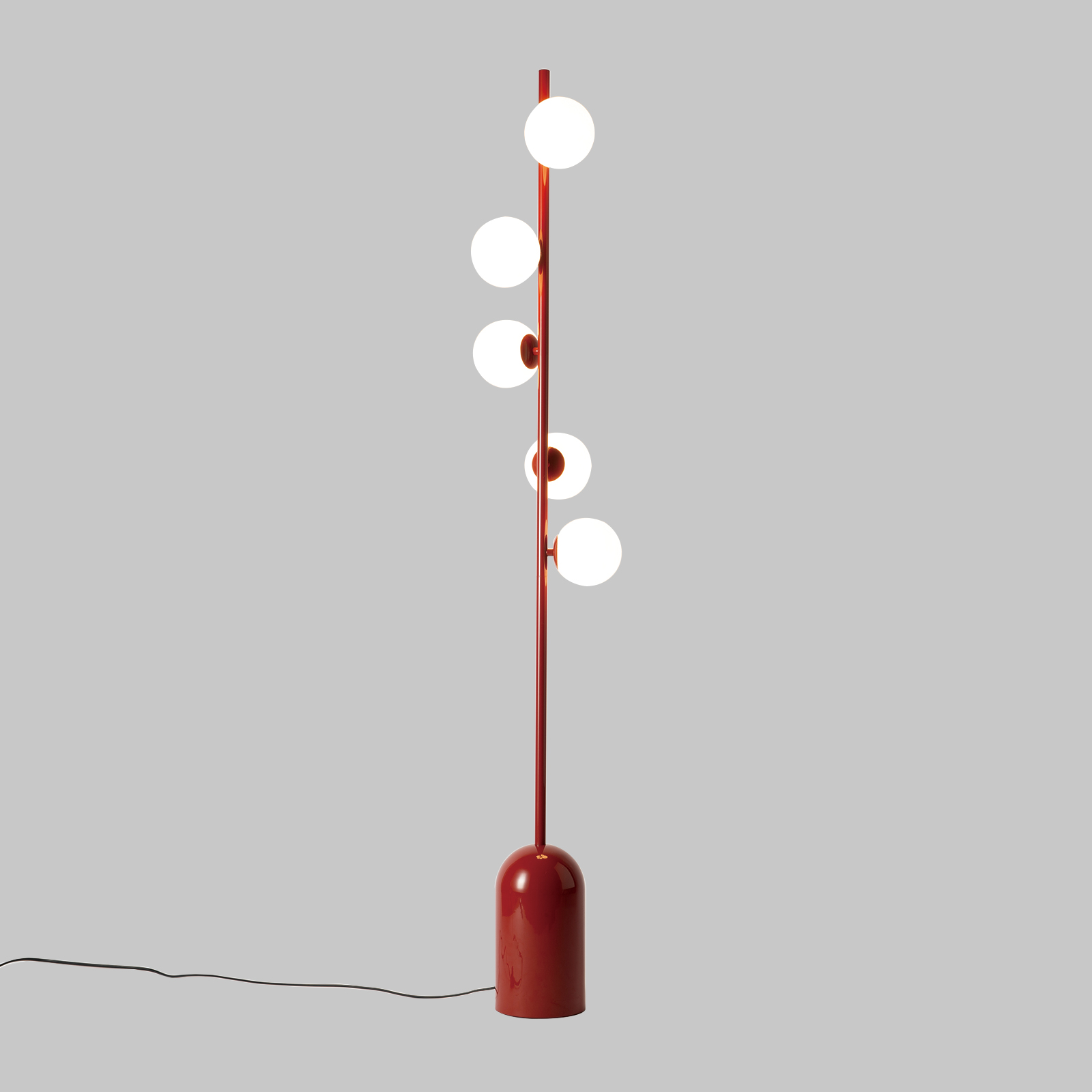Lámpara de pie roja con esferas de vidrio sobre fondo gris.