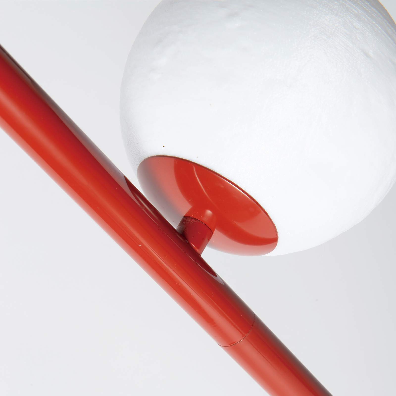 Un poste rojo sostiene una esfera blanca con base roja.