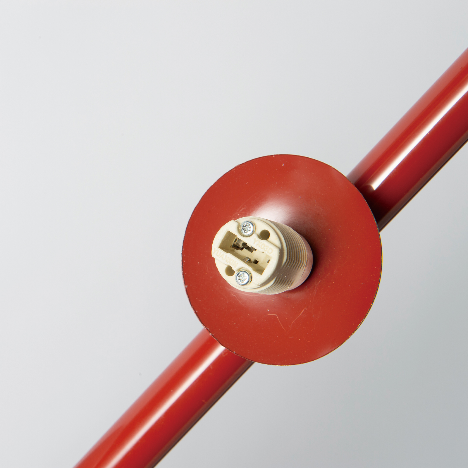Primer plano de una base de lámpara roja con portalámparas blanco.