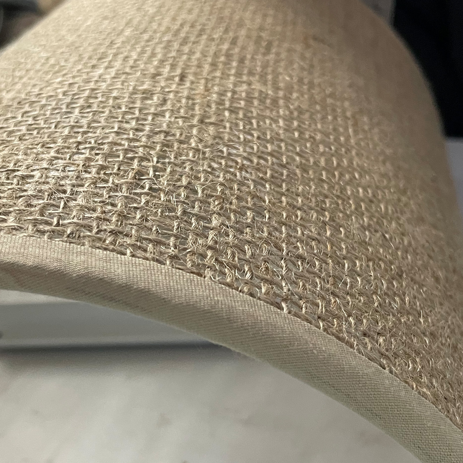Primer plano de tela de yute beige que muestra su textura tejida y un borde de tela.