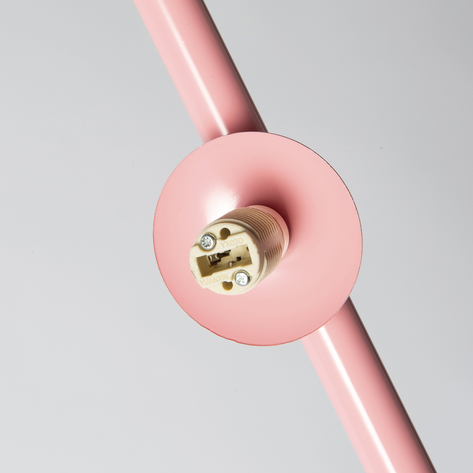 Primer plano de un portalámparas rosa con conexiones eléctricas y tornillos.