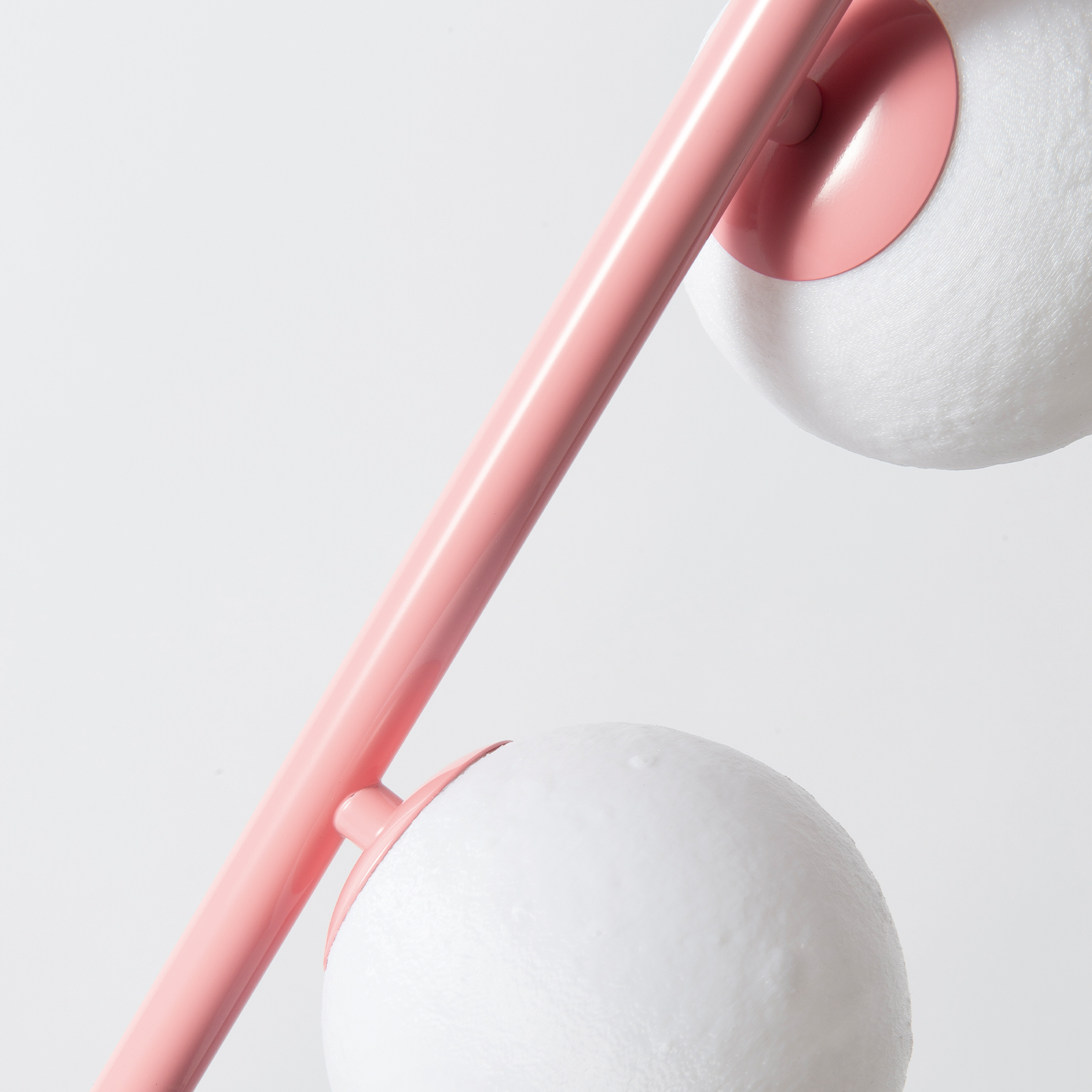Un brazo de lámpara rosa con dos pantallas esféricas blancas.