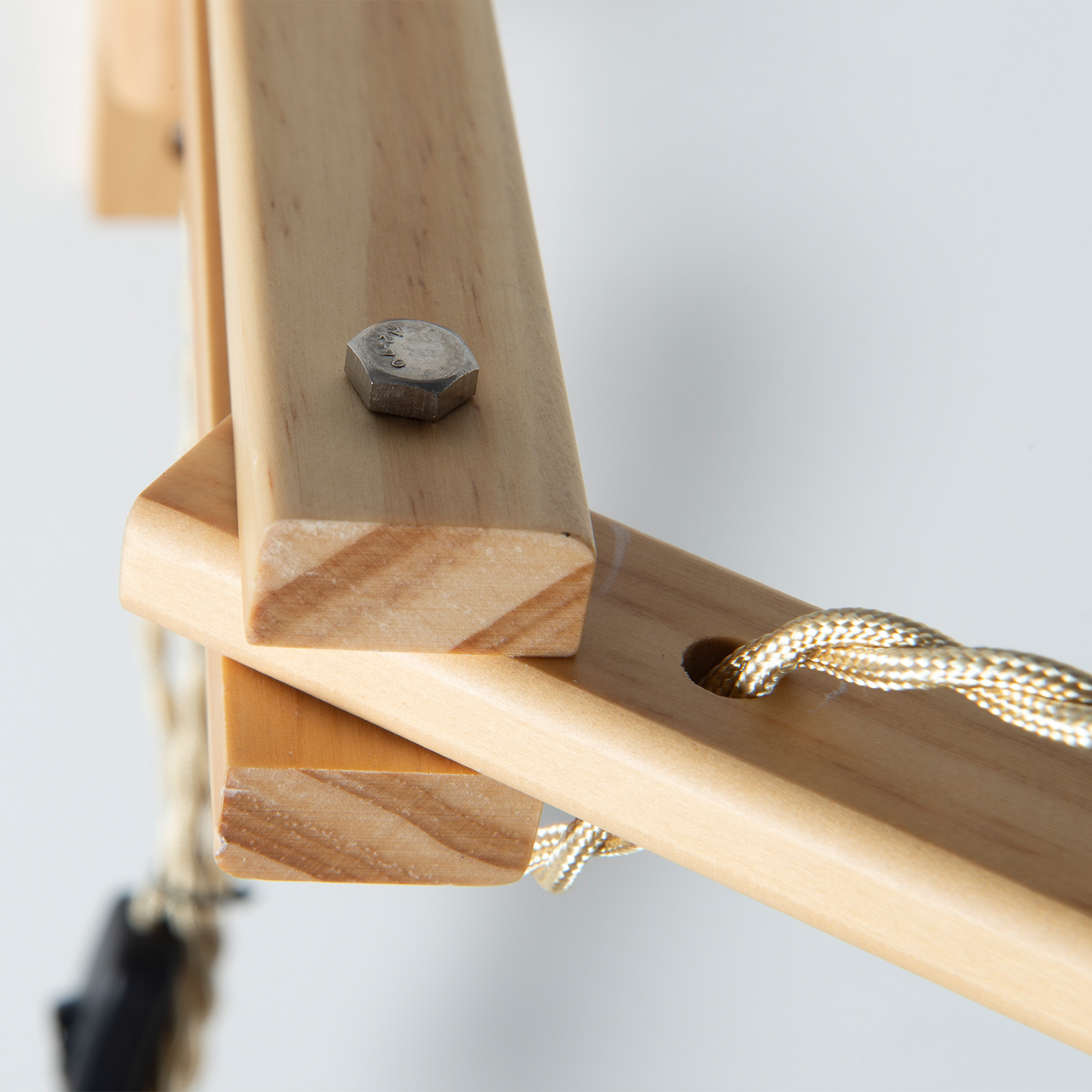 Un perno plateado sujeta dos piezas de madera. Un cable dorado pasa por un agujero.