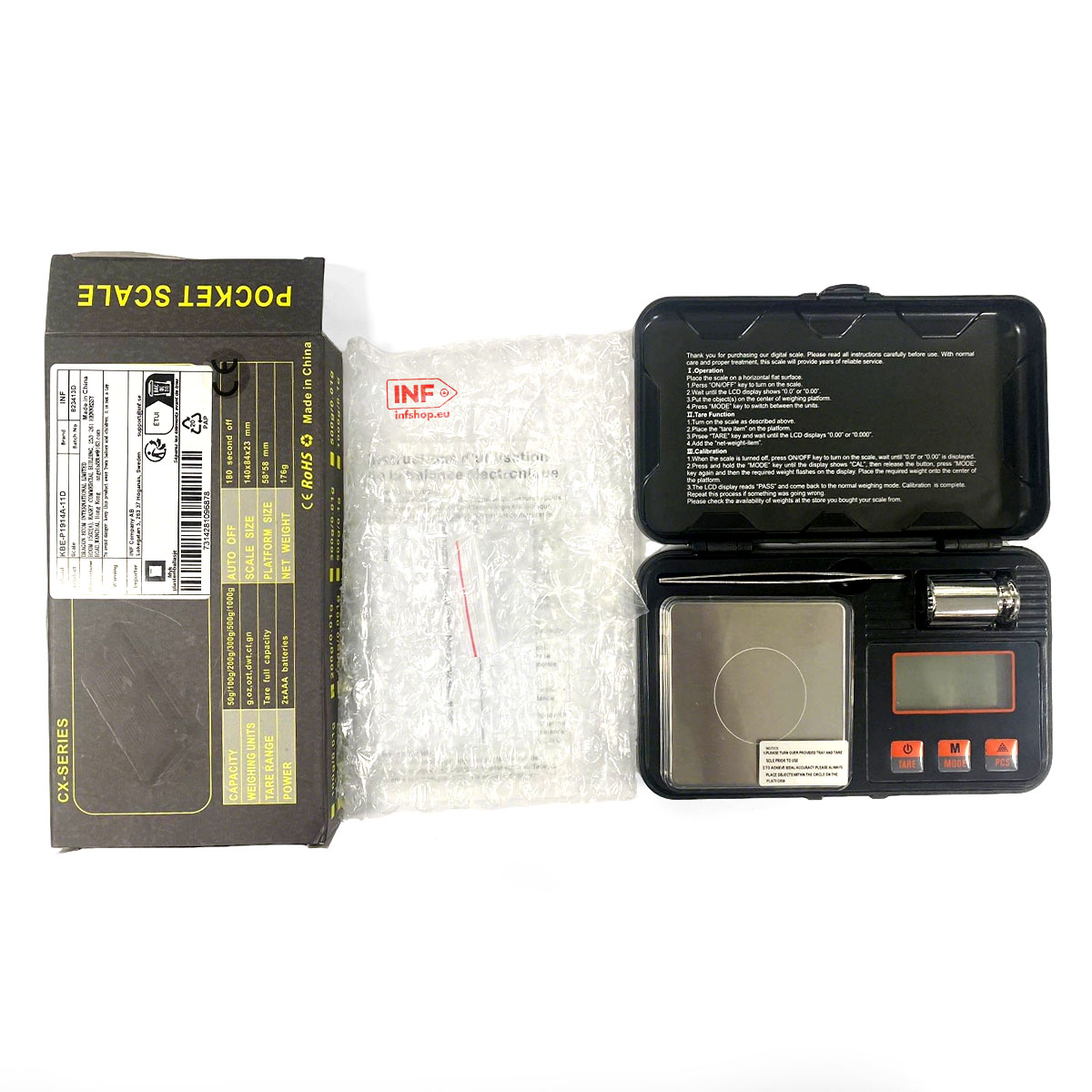 Eine digitale Waage, Zubehör und Verpackung liegen nebeneinander.