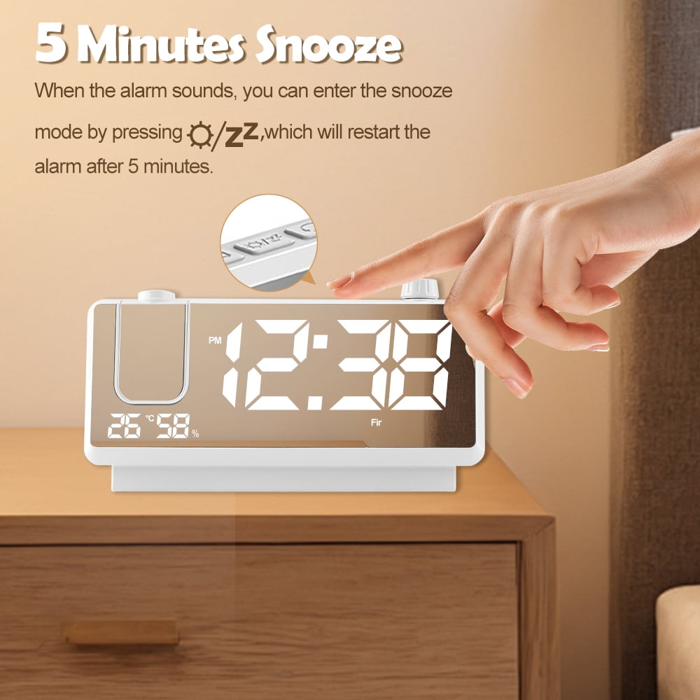 Eine Hand drückt den Snooze-Knopf eines digitalen Weckers, der 12:38 anzeigt.