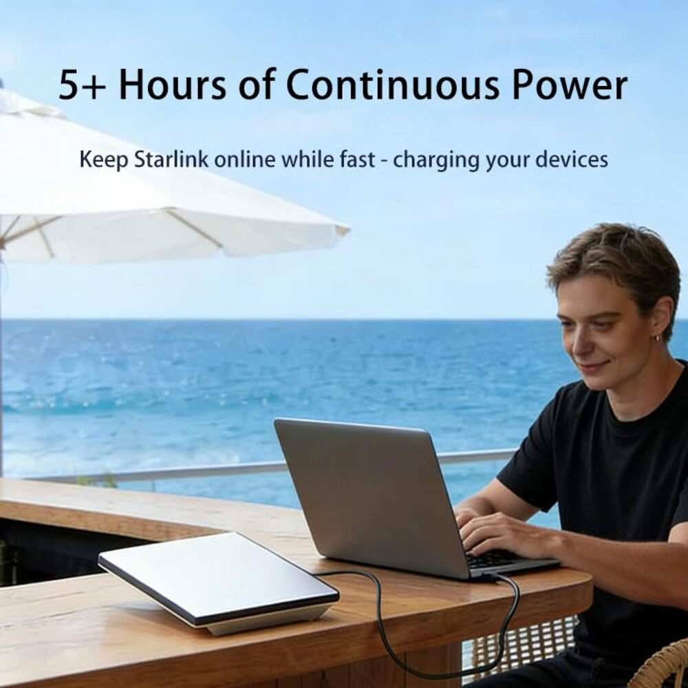Mann arbeitet am Laptop mit Powerbank am Meer unter Sonnenschirm.
