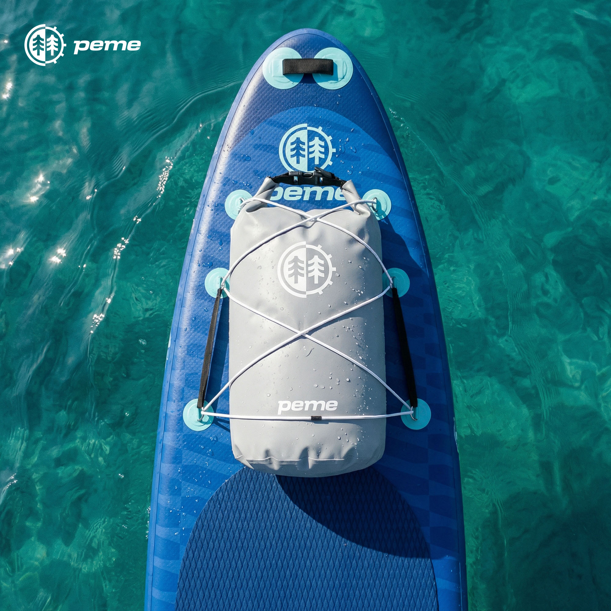 Een grijze dry bag is bevestigd aan een blauw paddleboard dat op helder water drijft.