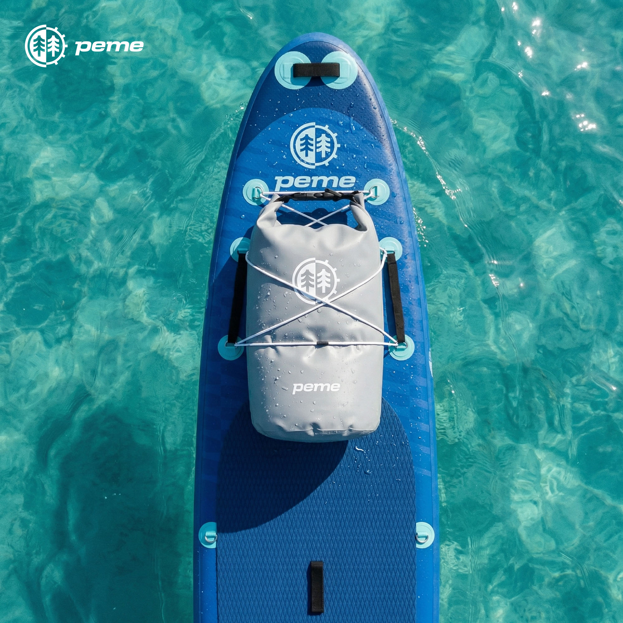 Een blauw paddleboard met een grijze drybag op turquoise water.