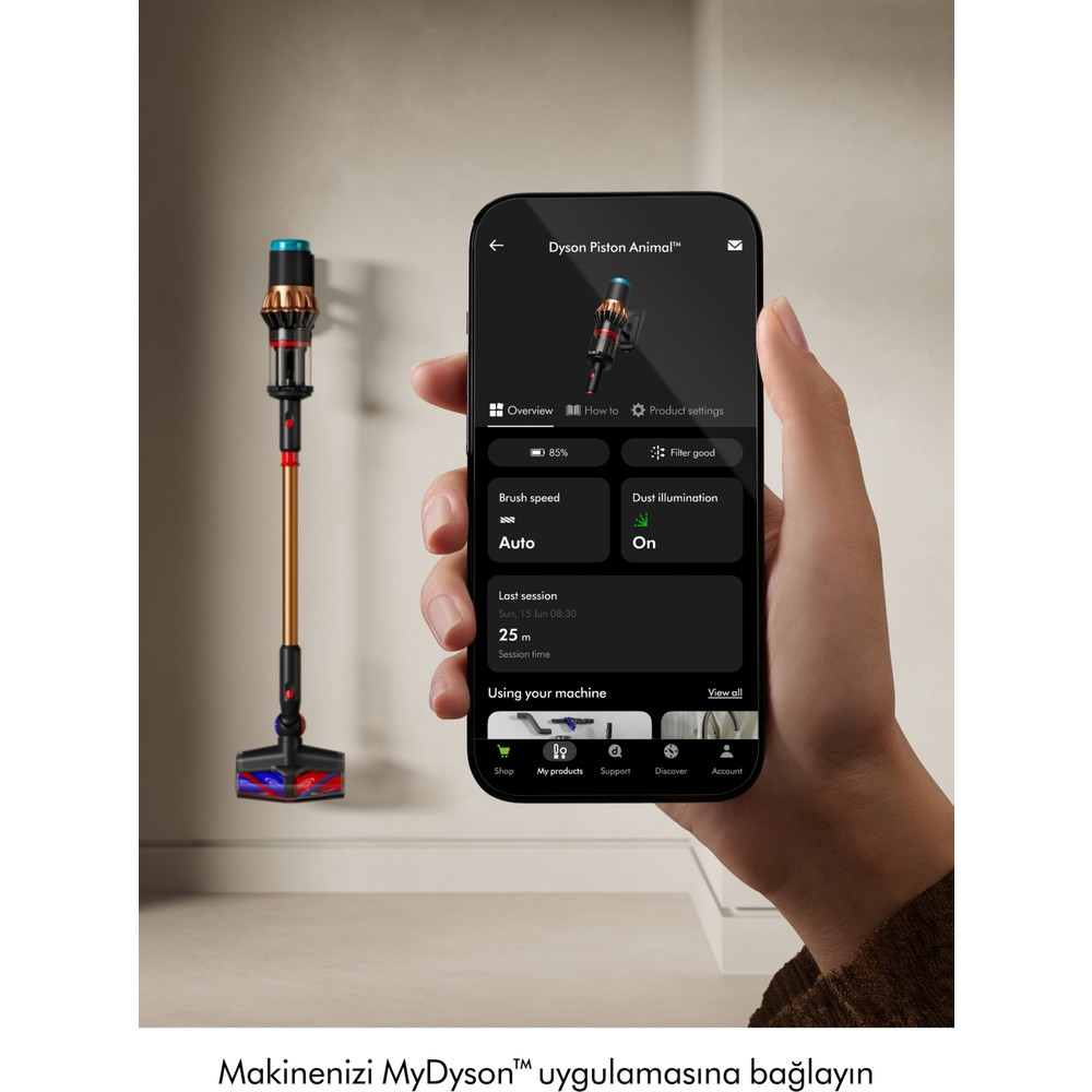 Una mano tiene uno smartphone che mostra l'app Dyson. Un aspirapolvere Dyson è a sinistra.