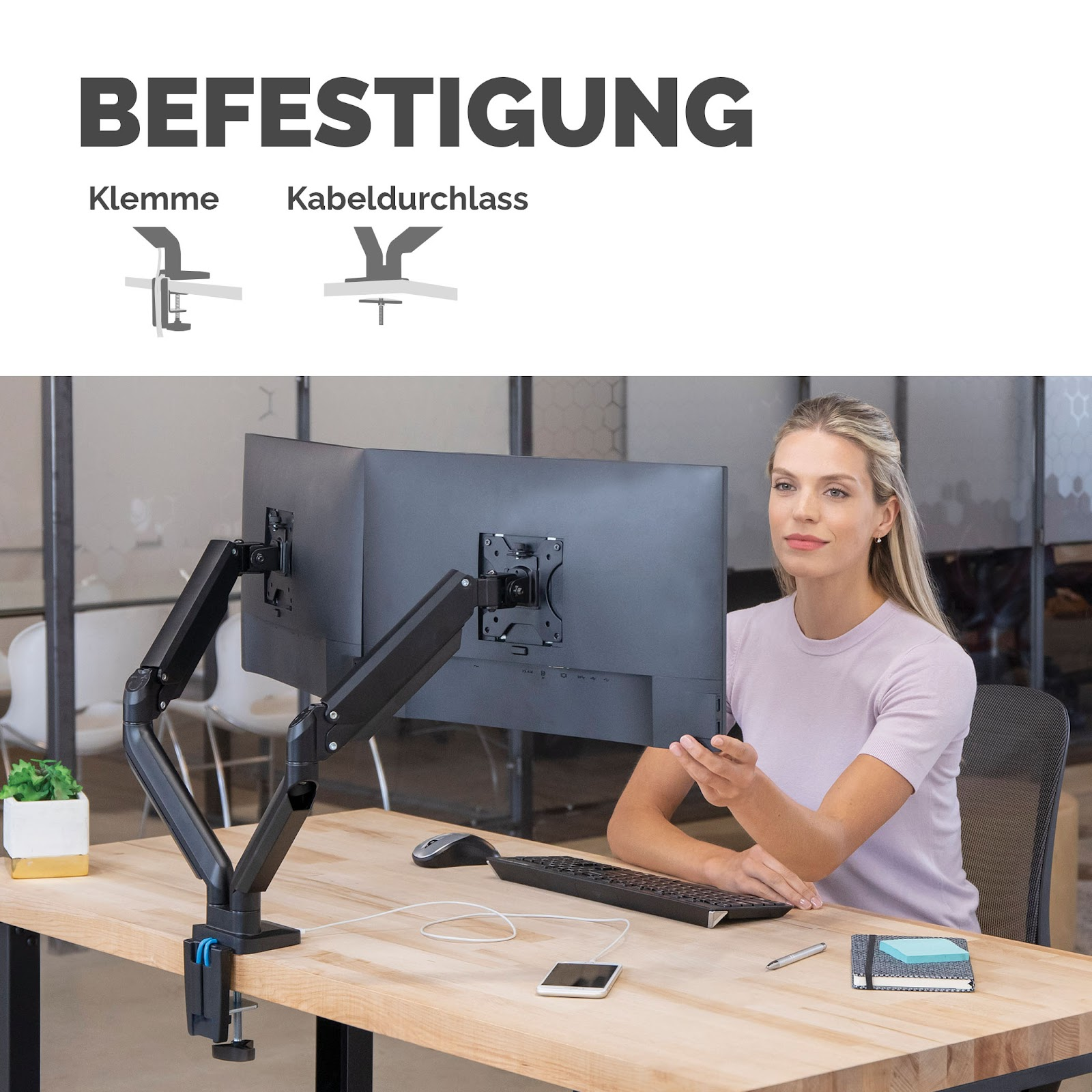 Woman at desk with dual monitor mount and accessories.
