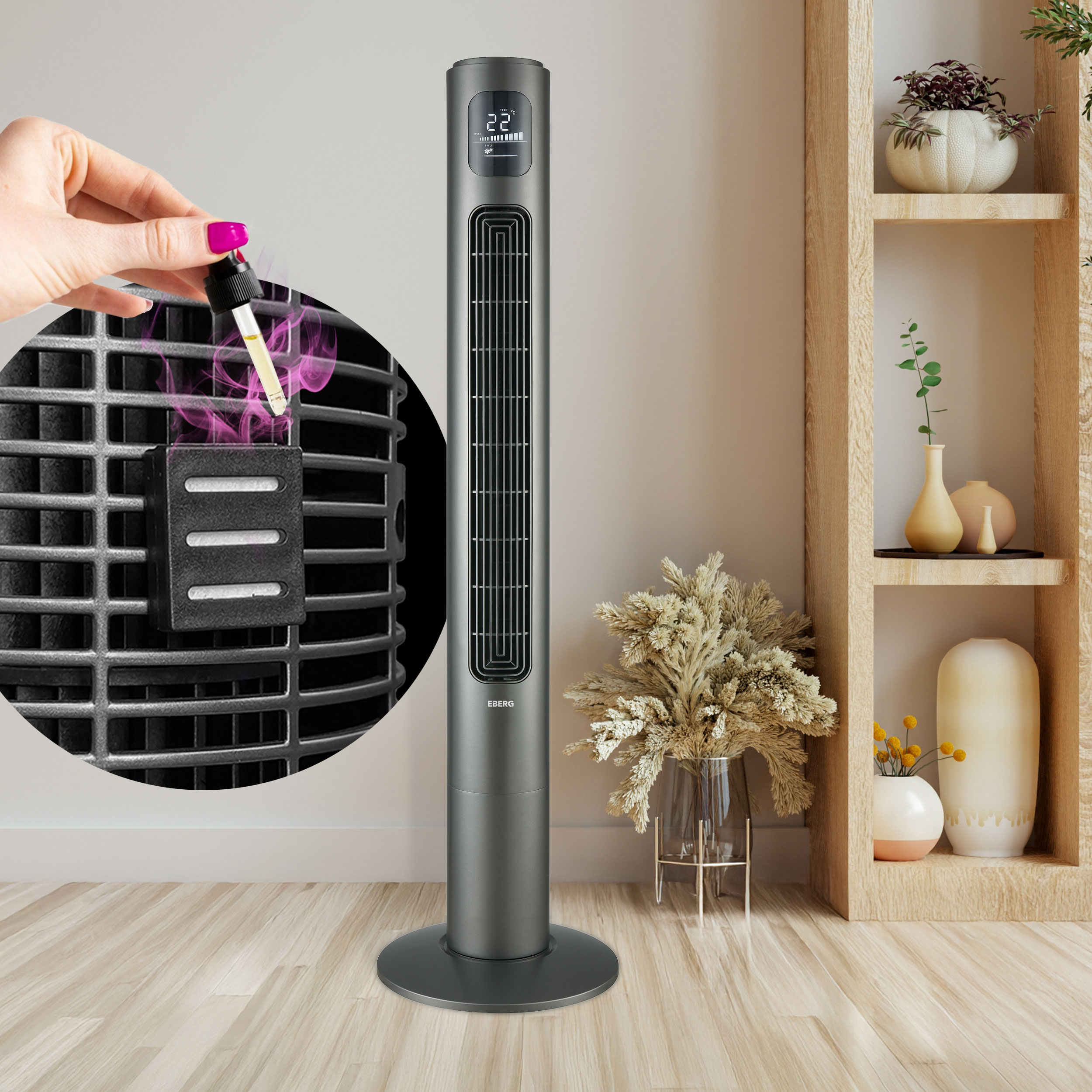 Szary wentylator wieżowy stoi na drewnianej podłodze. Ręka dodaje do niego olejek eteryczny.