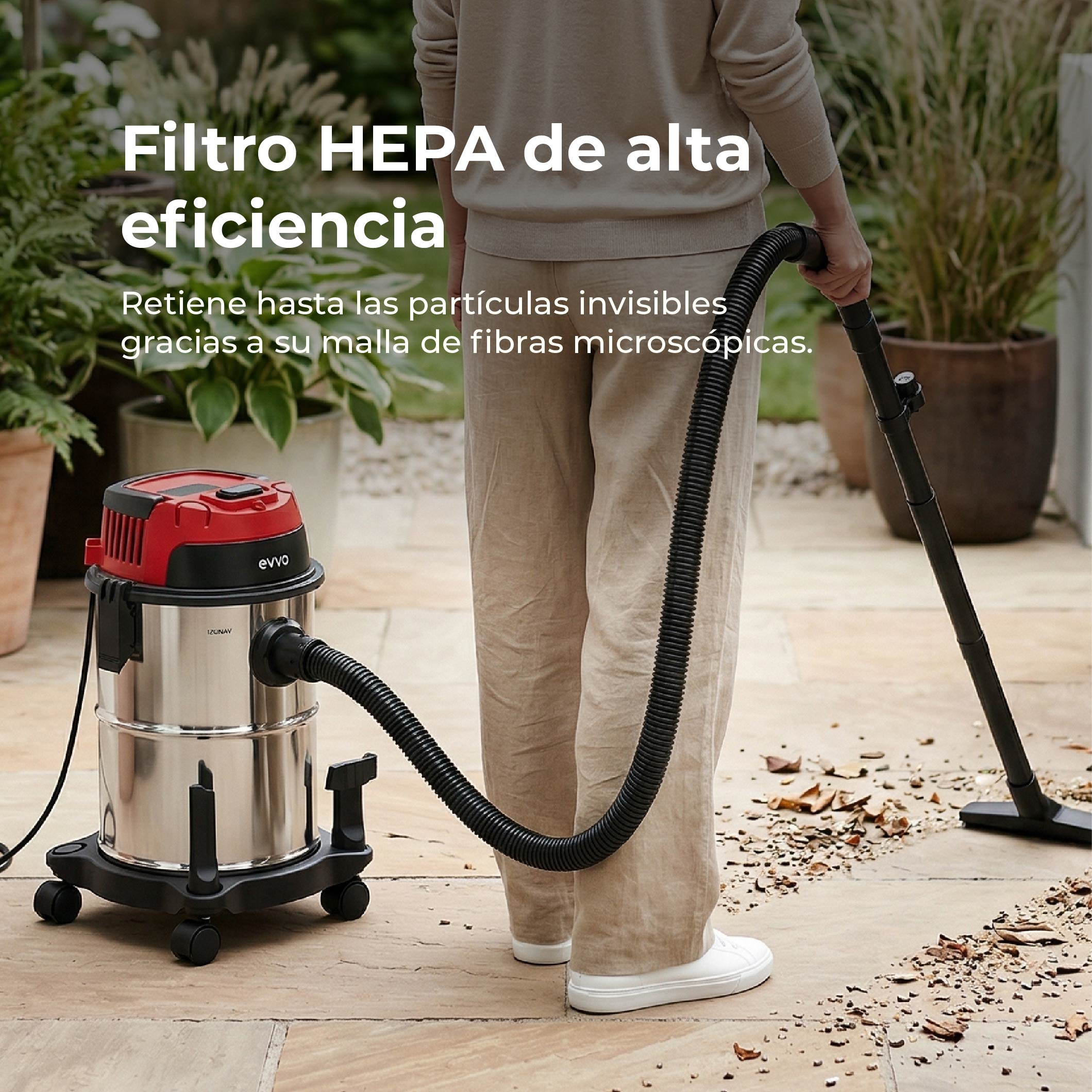 Una persona aspira con un'aspirapolvere per liquidi e solidi argentata e rossa su un patio di pietra.