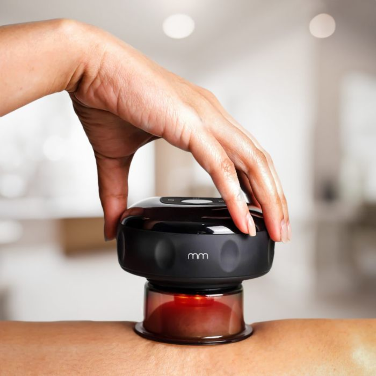 Hand houdt massageapparaat op huid. Donker lichaam, rood licht gloeit.