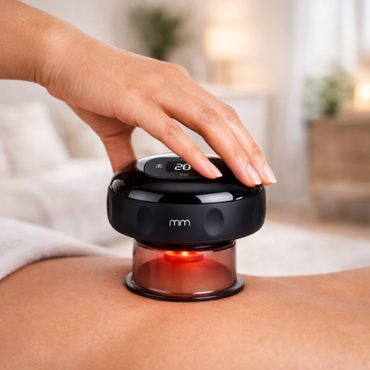 Een hand houdt een zwart massageapparaat met rood licht op de huid vast.