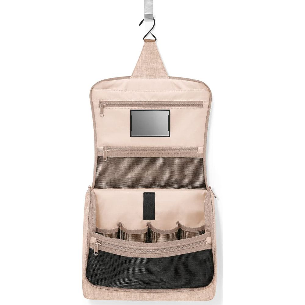 Eine beige Kulturtasche hängt an einem Haken, mit vielen Fächern und einem Spiegel.