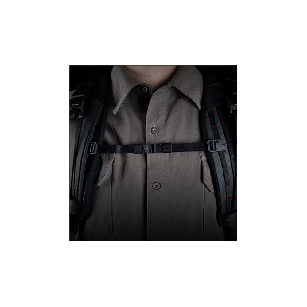 Gros plan d'une personne portant une chemise grise et une sangle de sac à dos noire.