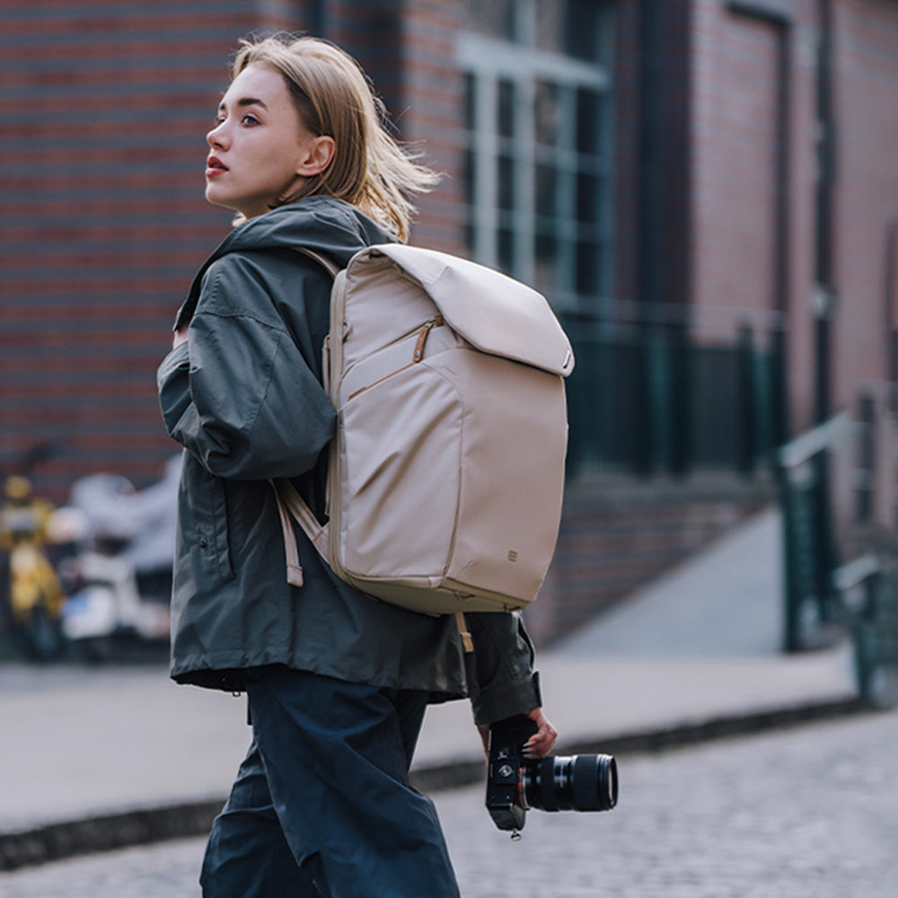 Femme avec sac à dos et appareil photo marche dans rue.