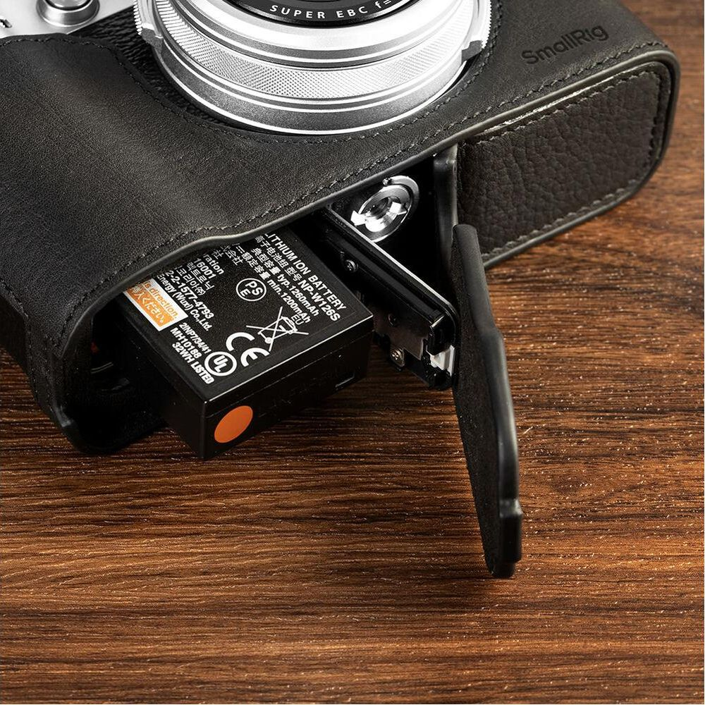 A black leather case covers a camera with its battery compartment open.