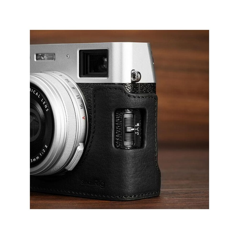 Close-up of a silver camera with a black leather half-case, on a wooden surface.