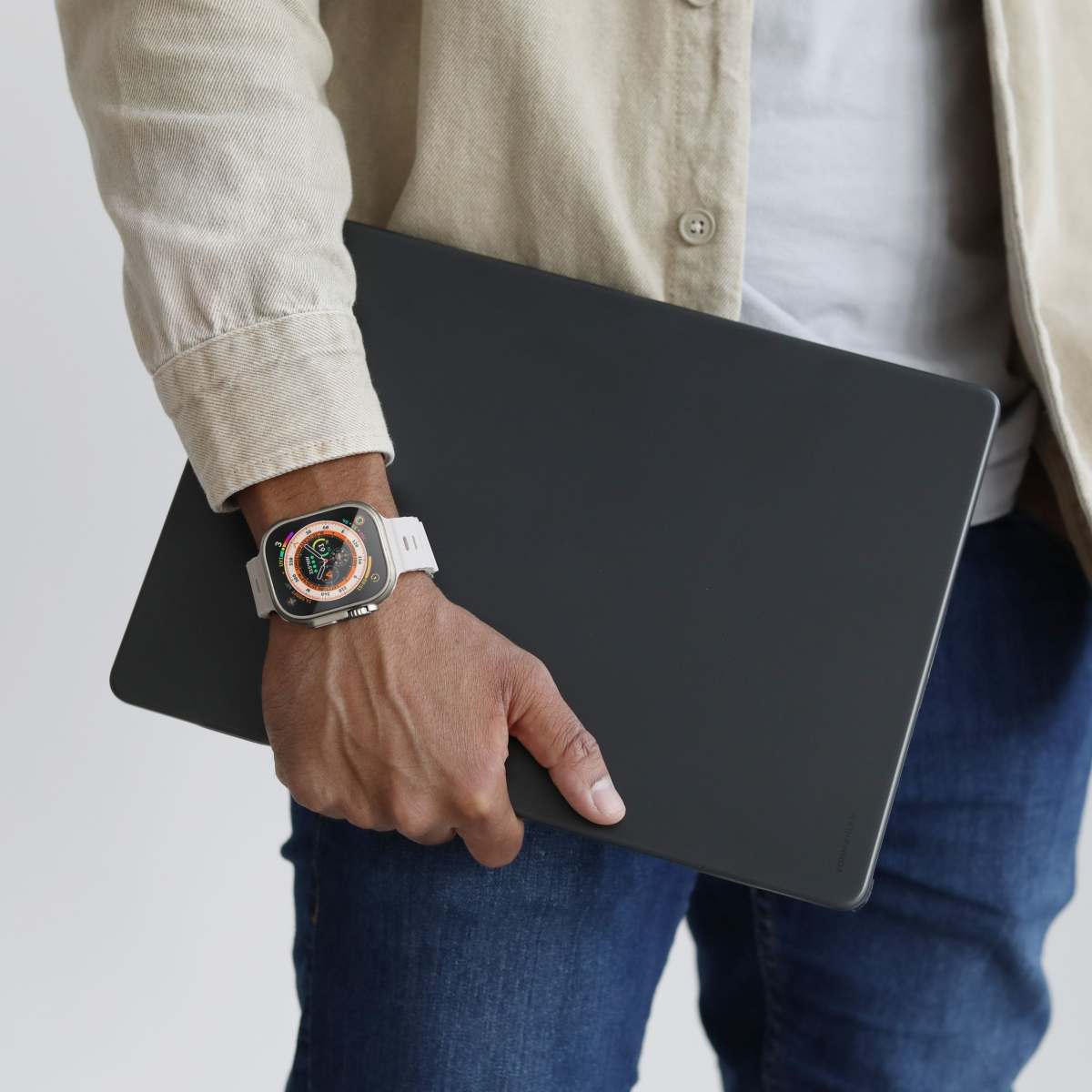 Eine Person mit einer Smartwatch und einem dunklen Tablet auf hellem Hintergrund.