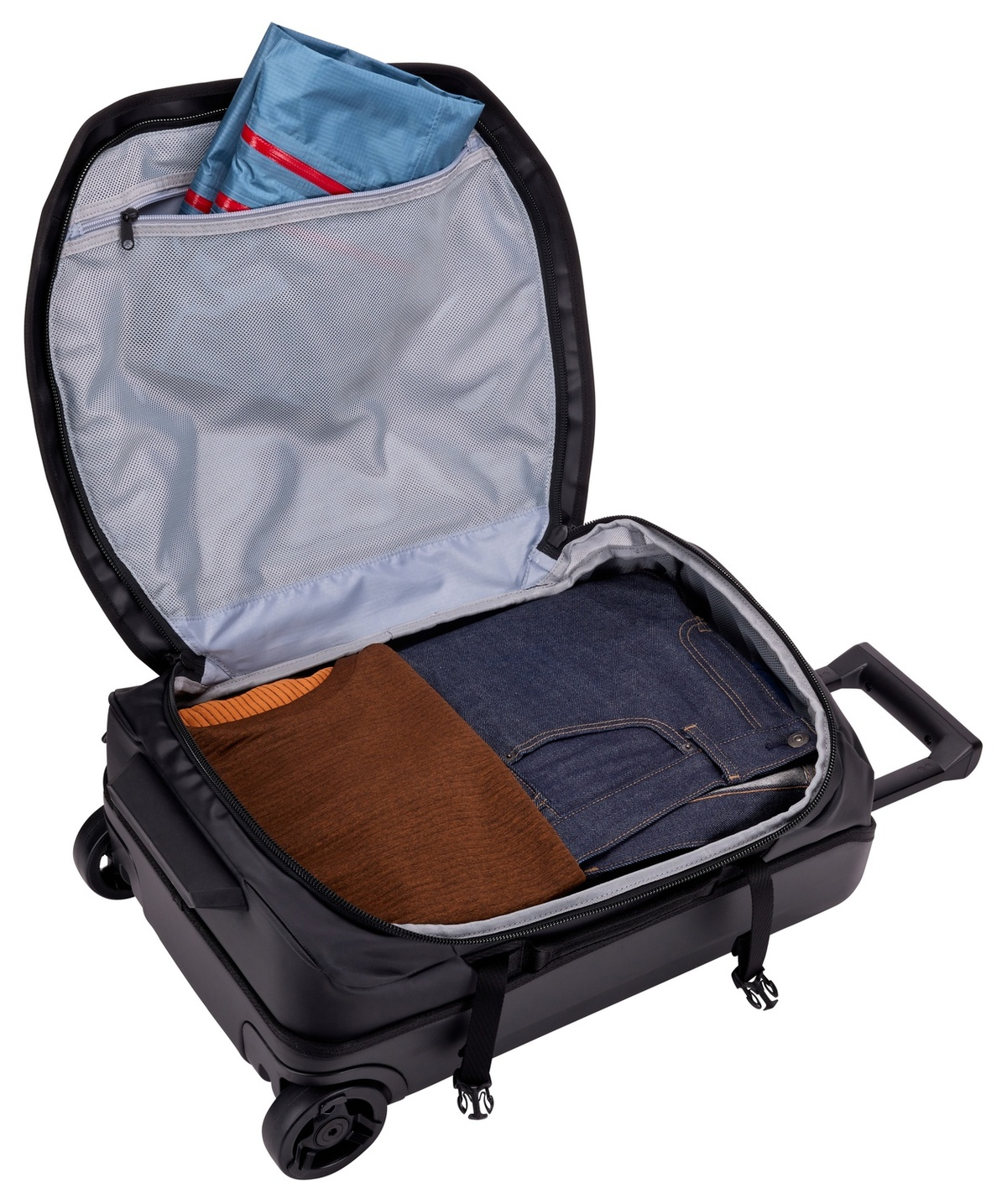 Ein offener schwarzer Koffer mit Kleidung: ein brauner Pullover und Jeans.
