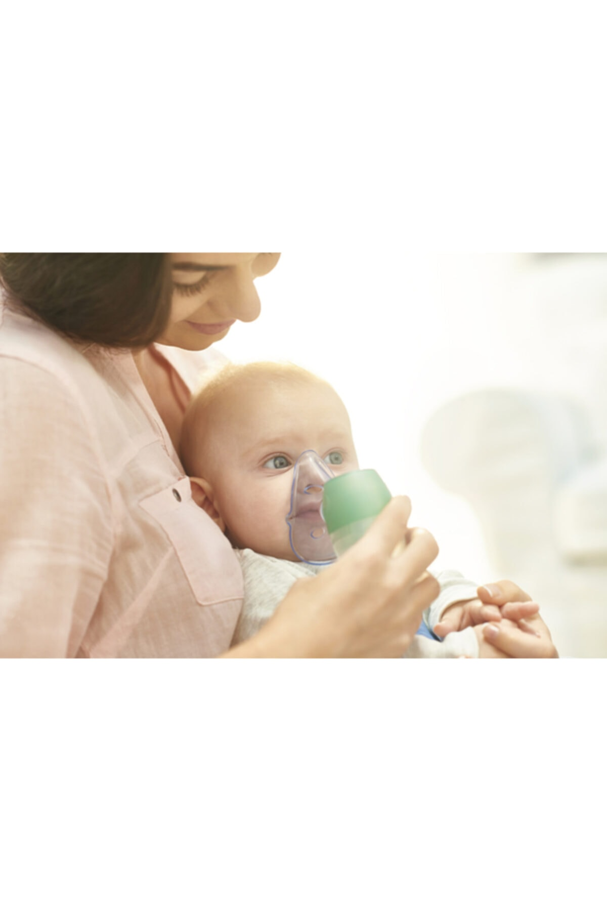 Anne, inhalatör maskeli bir bebek tutuyor.