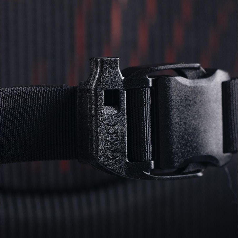 Gros plan d'une boucle noire sur une sangle noire. Fond sombre et texturé.