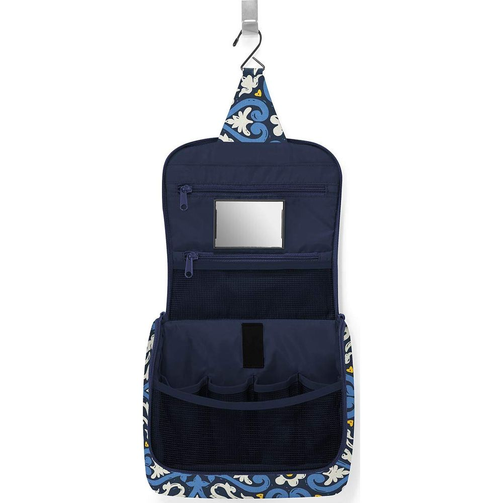 Eine aufklappbare Kulturtasche mit blauem Muster, die an einem Haken hängt.