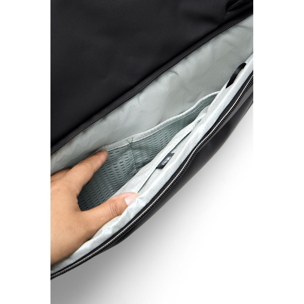 A hand reaches into a black compartment with gray mesh lining and multiple pockets.