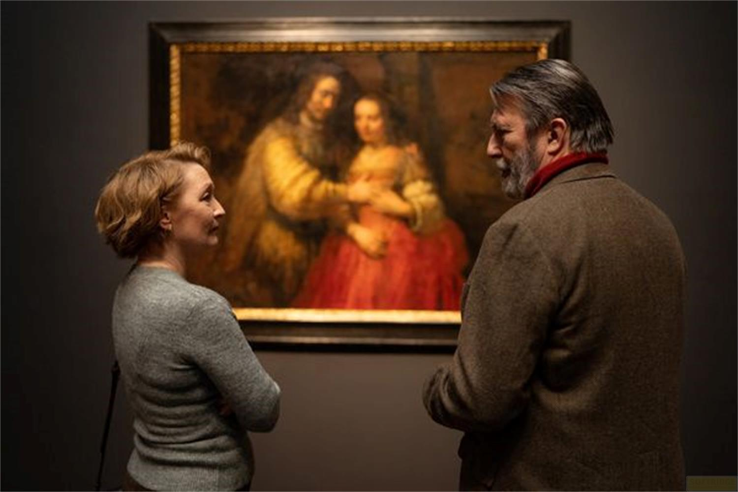 Un uomo e una donna davanti a un quadro con una figura rossa.