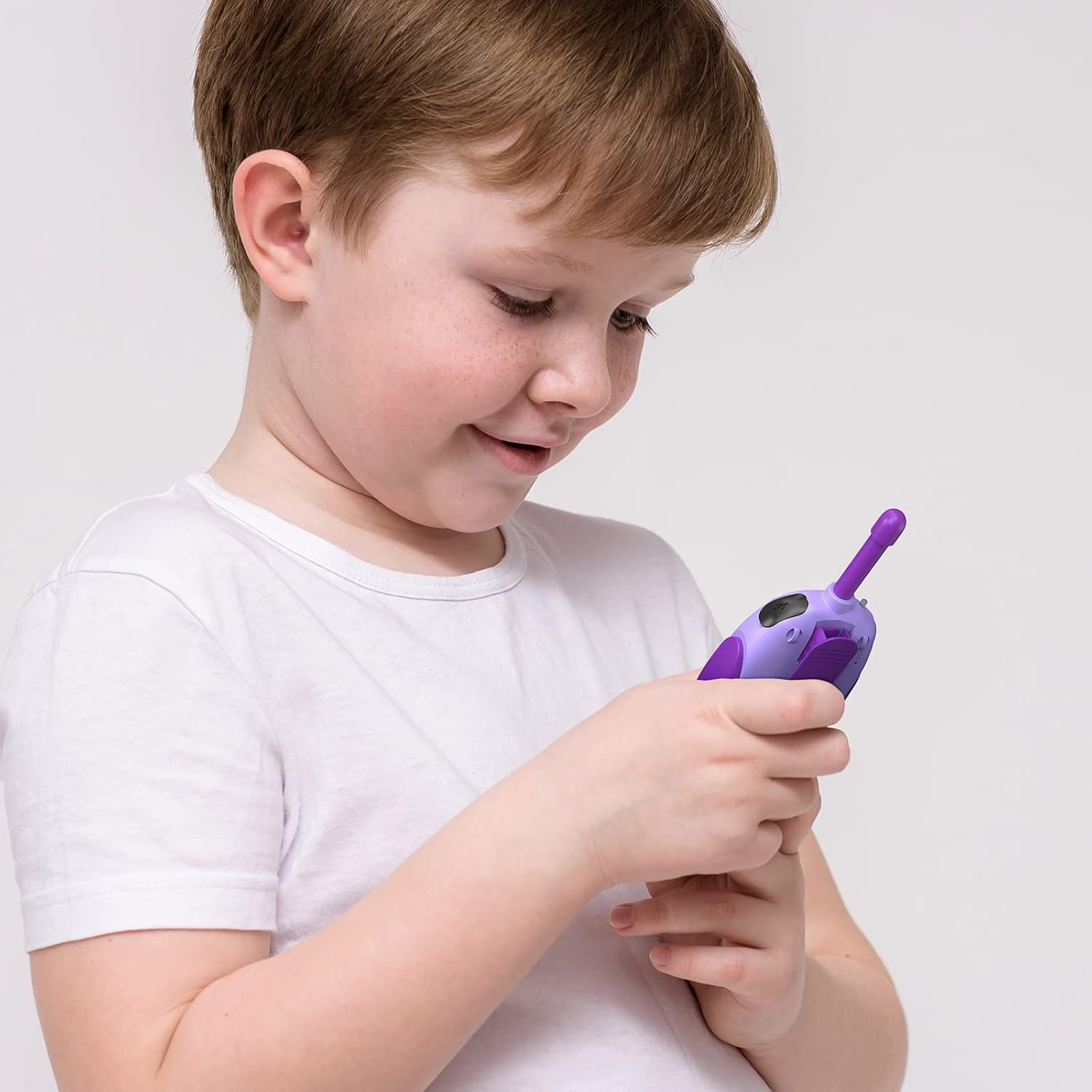Ein Junge mit Sommersprossen hält ein lila Walkie-Talkie.
