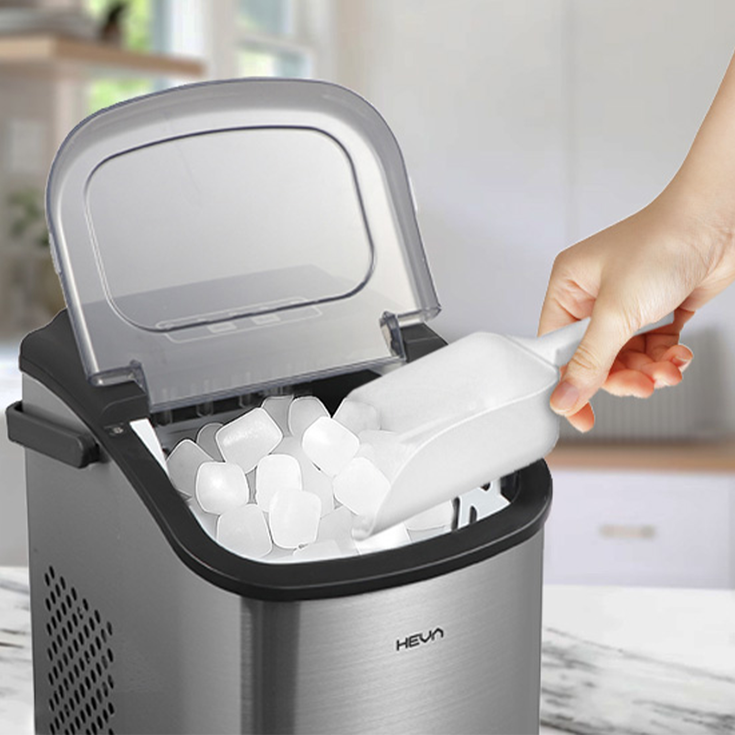 Ręka używa szufelki do wyjmowania kostek lodu z kostkarki.