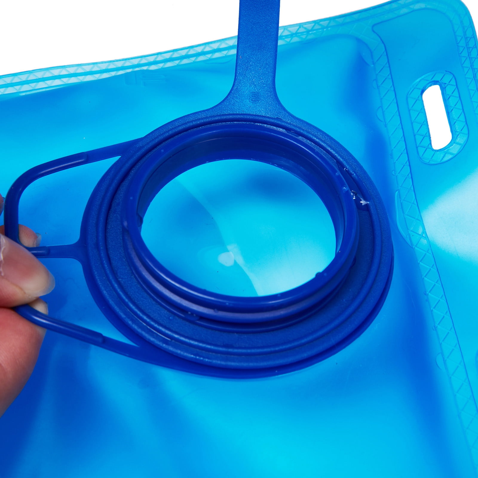 Eine Hand hält den blauen Deckel eines durchsichtigen Wasserbeutels.